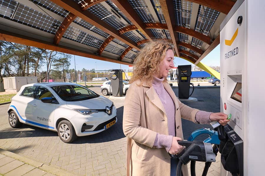 Een vrouw laadt haar elektrische deelauto op.