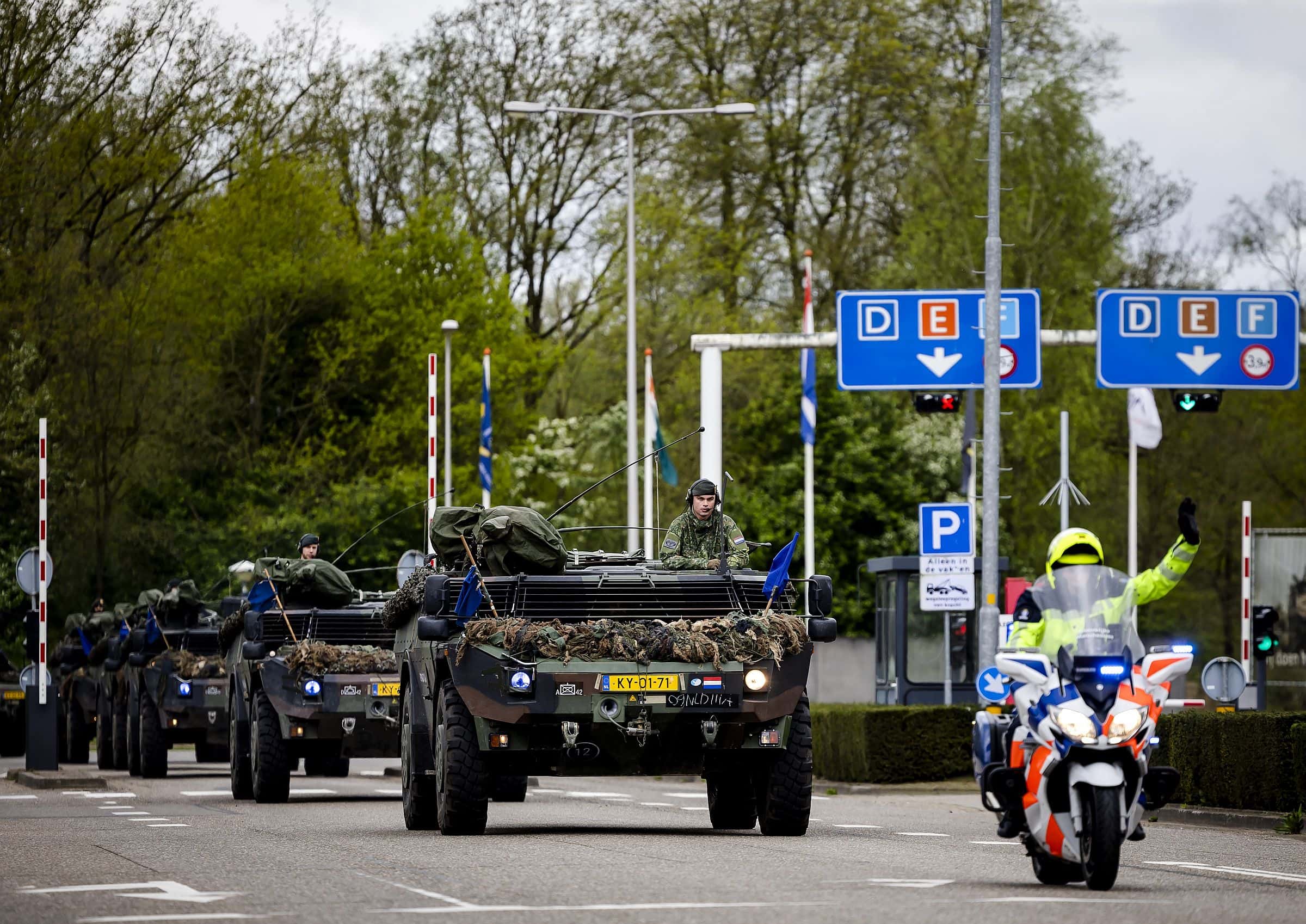 Tanks rijden onder politiebegeleiding in een colonne over een snelweg.