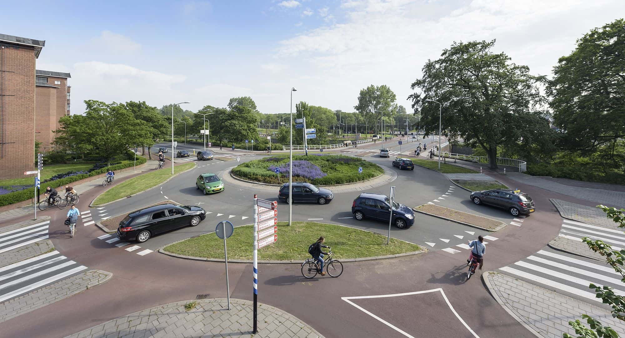 Auto's, fietsers en voetgangers rijden en lopen over een drukke rotonde